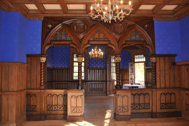 Neogotischer Innenraum von Schloss Wolfersdorf mit blauen Wänden und Holzvertäfelung